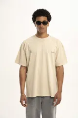 Remera color arena de corte holgado con cuello redondo y manga corta. Presenta un pequeño estampado en el frente.