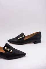 Chatitas negras de cuero con punta fina y apliques de tachas doradas.