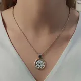 Gargantilla con cadena de eslabones plateados y dije circular con borde dorado y centro de nácar calado.