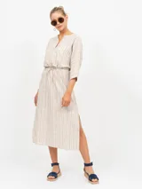 Túnica midi de lino color crudo con finas rayas verticales en tono marrón. Presenta cuello en V con abertura y mangas tres cuartos. La cintura se ajusta con un lazo del mismo tejido, y tiene aberturas laterales en el ruedo.