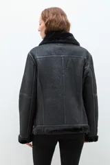 Chaqueta negra simil gamuza con interior de piel sintética, cuello con solapas y cierre asimétrico con cremallera.