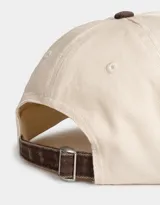 Gorra de béisbol color beige con visera marrón y bordado frontal con la frase "Express Yourself" en marrón. Cuenta con botón superior marrón y regulador trasero metálico.
