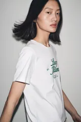 Camiseta blanca de algodón con cuello redondo y mangas cortas. Estampado frontal con la frase "Paris, Mon doux rêve!" en azul marino.