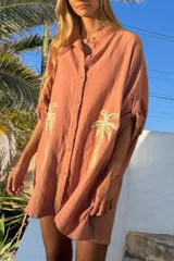 Túnica color salmón de algodón bambula con bordado de palmeras doradas, corte holgado, cuello camisero y mangas 3/4 con botón.