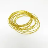 Pulsera dorada de bronce, compuesta por múltiples pulseras finas entrelazadas.