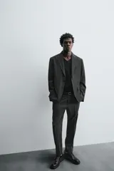 Blazer regular fit color gris oscuro con diseño de cuadros, confeccionada en tejido con lana. Tiene cuello con solapas de muesca, manga larga con puños abotonados, bolsillo de vivo en el pecho, bolsillos de solapa en la cadera, bolsillo interior, aberturas en la espalda y cierre frontal con botones.