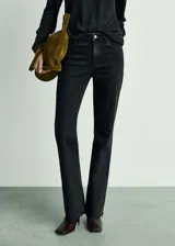 Pantalón de jean negro de tiro medio, corte flare y bajo deshilachado.