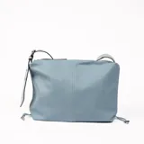 Bolso bandolera de cuero sintético color celeste, con textura granulada y correa ancha con ojales metálicos.