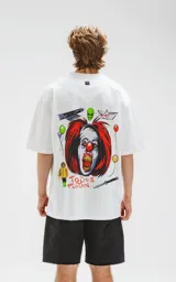 Remera blanca de corte oversize con estampado del payaso Pennywise de la película IT, con globos, un barco de papel, un niño con impermeable amarillo y la frase "Todos Flotan".