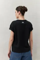 Remera blanca de manga corta con estampado floral en tonos dorados en el frente.