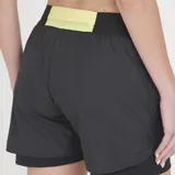 Short de running para mujer de Le Coq Sportif, color negro, con diseño de doble capa: una capa exterior ligera y una capa interior tipo calza. Presenta cintura elástica ancha y el logo del gallo en dorado en el muslo izquierdo.