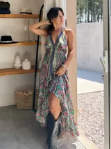 Vestido largo con estampado floral, escote halter y corte asimétrico con volados.