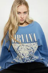 Buzo celeste de algodón con cuello redondo y mangas largas. Estampado frontal con el logo de la banda Nirvana y la imagen de la portada del álbum Nevermind.