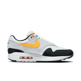 Championes Nike Air Max 1 de hombre, color blanco con detalles en gris, negro y naranja. Presentan la tecnología Air Max en la suela para mayor amortiguación.