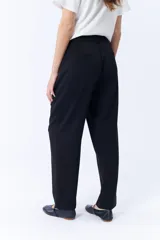 Pantalón de vestir negro, de corte carrot, con pinzas en la cintura y bolsillos laterales.