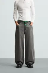 Pantalón de jean gris de corte amplio, estilo balloon fit, con cinco bolsillos, cierre frontal con cremallera y botón, y efecto de color lavado en toda la prenda.