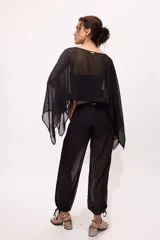 Pantalón negro traslúcido con corte ancho y ajuste en los tobillos.