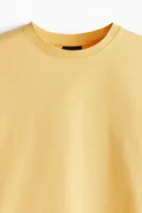 Remera de algodón color amarillo, de corte holgado, con cuello redondo ribeteado, hombros caídos y bajo recto.
