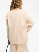 Blazer color durazno con pequeños lunares brillantes, cuello solapa, cierre con un botón frontal, bolsillos delanteros y corte clásico.