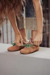 Zapatillas urbanas de cuero color tostado, con cordones verdes y suela de goma.