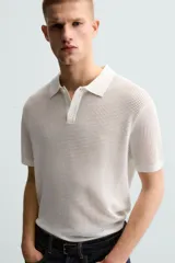 Polo blanco de punto tejido con estructura calada, corte regular fit, cuello solapa con abertura frontal y manga corta.