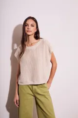 Chaleco de punto calado color beige, con cuello redondo y sisas amplias.