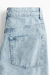 Pantalón jean de tiro bajo en denim bouclé celeste, de algodón rígido, con cinco bolsillos, cierre con botón y corte holgado con piernas amplias.