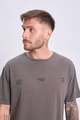 Remera de manga corta gris oscuro, corte oversize, con estampado frontal que incluye un logo con tipografía futurista, un globo terráqueo y un emoticón.
