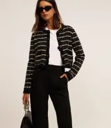Pantalón de vestir negro de corte wide leg, confeccionado en crepé. Presenta cintura con trabillas, detalle de solapa con botón y bolsillos laterales.