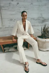 Pantalón de vestir color beige, de tiro alto, con cintura elástica en la parte trasera, bolsillos delanteros y falsos bolsillos de vivo en la parte trasera.