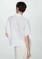 Camisa blanca de lino con cuello clásico, manga corta y cierre frontal con botones.
