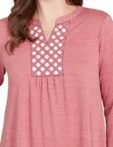 Blusa de manga tres cuartos color rosado, confeccionada en modal texturizado. Presenta un escote en V con cuello a la base y apliques nacarados en el área del escote.