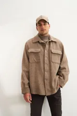 Camisa estilo leñadora marrón con diseño de espiga, cuello clásico, abrochadura frontal a la vista, bolsillos plaqué con tapa en el pecho, mangas largas con puño y botón.