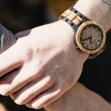 Reloj de pulsera para hombre, con caja y correa de madera clara. Esfera con números romanos grabados con láser y manecillas negras.