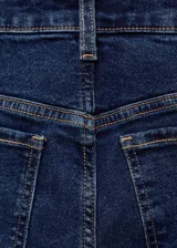 Jeans de tiro alto color azul oscuro, corte cropped y acampanado, con cinco bolsillos y cierre de cremallera y botón.