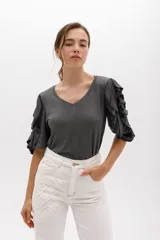 Remera color beige con mangas cortas y volados con borde naranja.