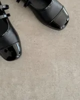 Ballerinas negras de cuero vegano con puntera charolada y doble tira sobre el empeine.