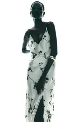Vestido largo blanco con estampado de flores negras, escote pico y tirantes finos con ribete negro.