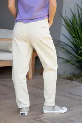Pantalón jean de corte mom color crudo, con tiro alto, cinco bolsillos y cierre frontal con botón y cremallera metálica.