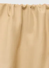 Falda larga color beige, de tiro bajo y corte evasé, con cintura elástica y bolsillos laterales.