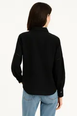 Camisa negra de manga larga con cuello clásico y cierre frontal con botones.