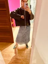 Sweater de cuero color marrón oscuro con cuello redondo y cierre frontal con botones blancos.