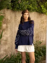 Buzo de algodón color blanco roto, de corte holgado, con puños y tajos laterales. Presenta un bordado artesanal en relieve de líneas orgánicas en color marrón caramelo sobre las mangas.