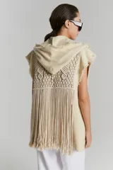 Chaleco largo color beige de tejido rústico de algodón con macramé aplicado y capucha. Terminaciones al corte, desflecadas.