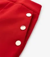 Bermuda roja de crepé con cierre delantero, bolsillos laterales con botones y pliegues.