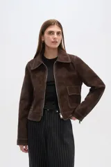 Chaqueta marrón de gamuza con cuello camisero, cierre frontal con cremallera, bolsillos de parche y costuras en contraste.