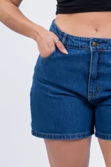 Short de jean de tiro alto, color azul medio, con bolsillos delanteros y traseros, y ruedo desflecado.