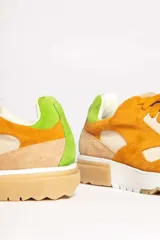 Zapatillas deportivas color mostaza con detalles en beige, verde y blanco.