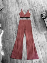 Conjunto de top y pantalón palazzo con estampado de rayas verticales color ladrillo y blanco. El top es de corte triangular con tirantes finos y el pantalón es de tiro alto y corte acampanado.