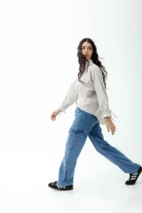 Pantalón cargo de jean celeste con lavado esfumado, tiro bajo, pierna ancha y bolsillos cargo.